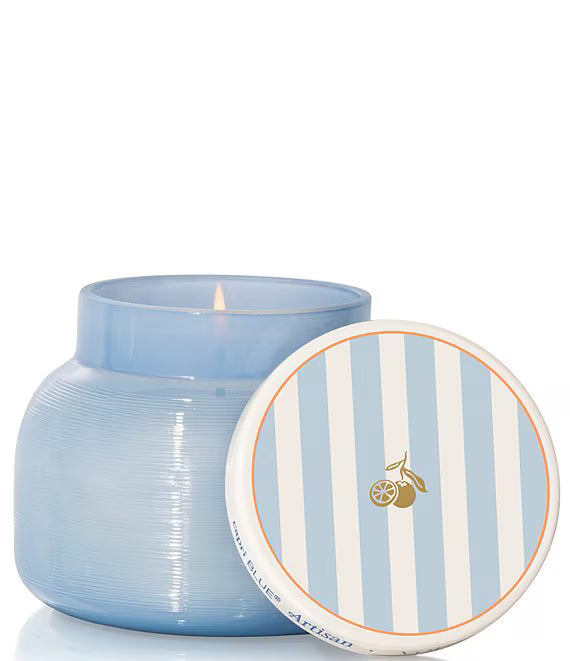 Blue candle in a textured jar with a striped lid on a white background