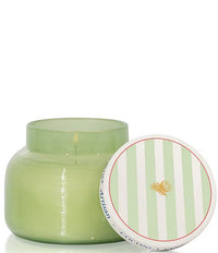Green candle in a glass jar with a striped lid on a white background