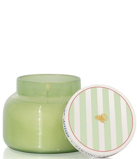 Green candle in a glass jar with a striped lid on a white background