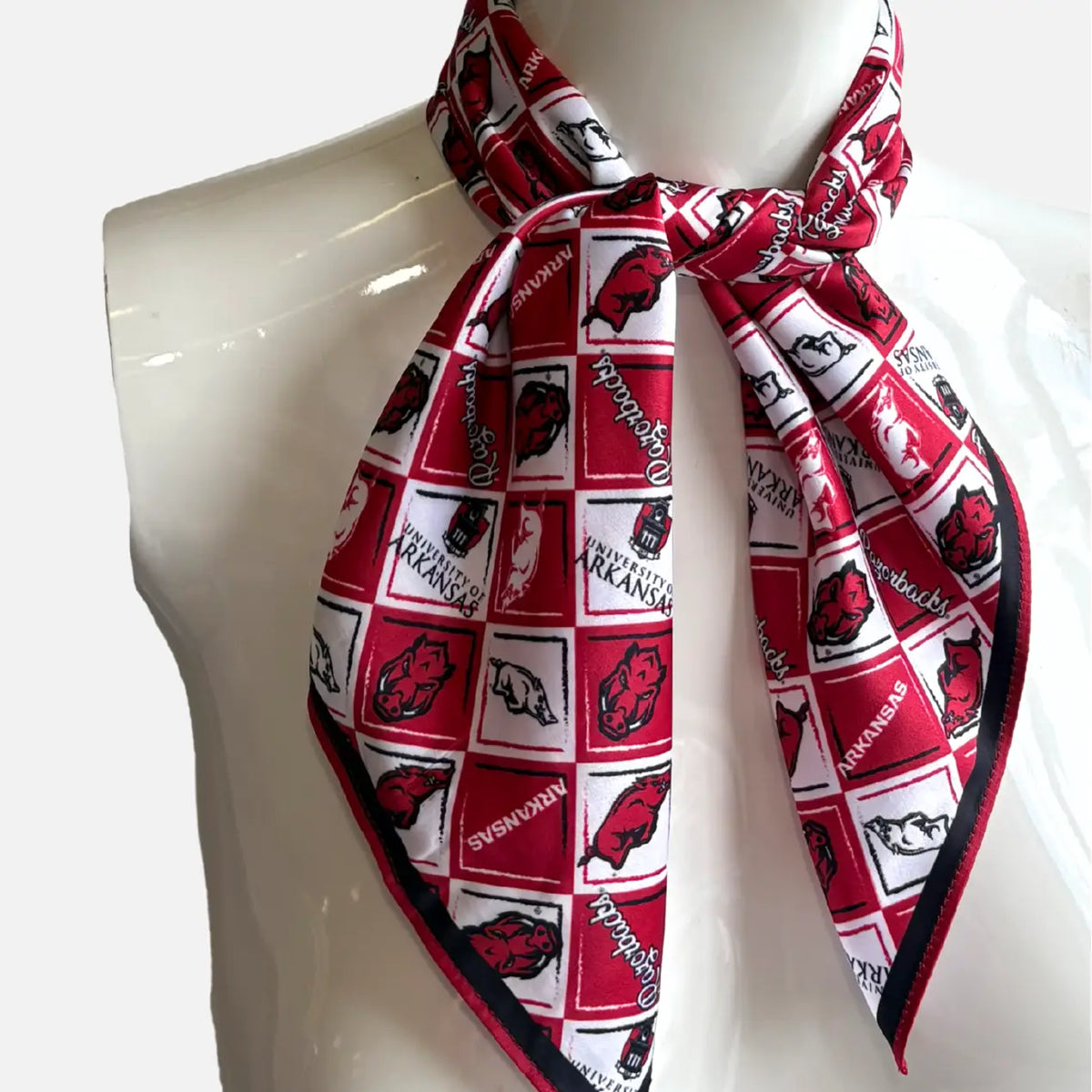 A square scarf with a red and white University of Arkansas Razorbacks pattern, tied around the neck of a white mannequin torso.