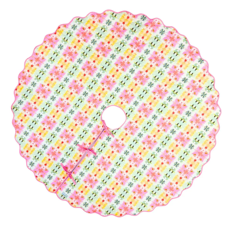 A round, scalloped-edge fabric tree skirt featuring a colorful floral and horseshoe pattern on a white background.