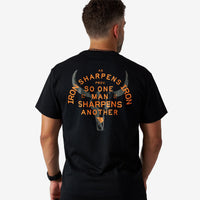 Man wearing a black t-shirt with orange text and graphic on the back, standing against a white background.