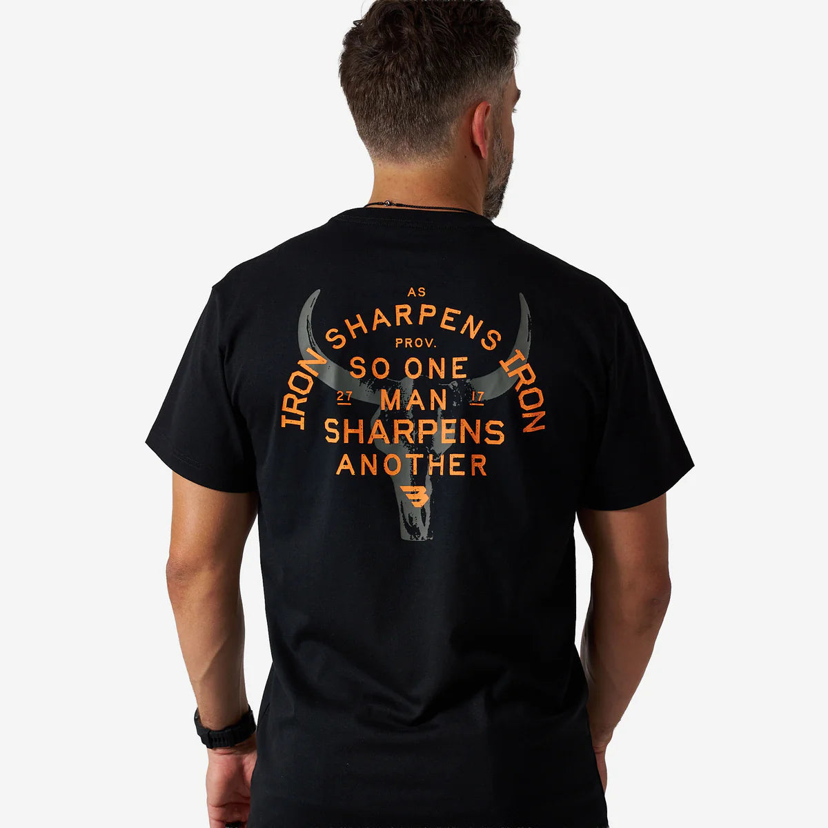 Man wearing a black t-shirt with orange text and graphic on the back, standing against a white background.