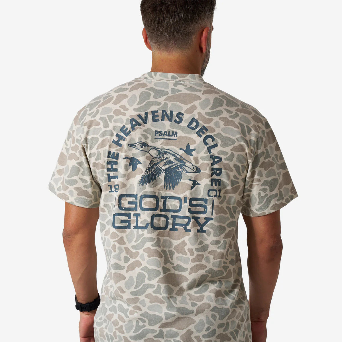 Man wearing a camouflage t-shirt with text and graphic design on the back