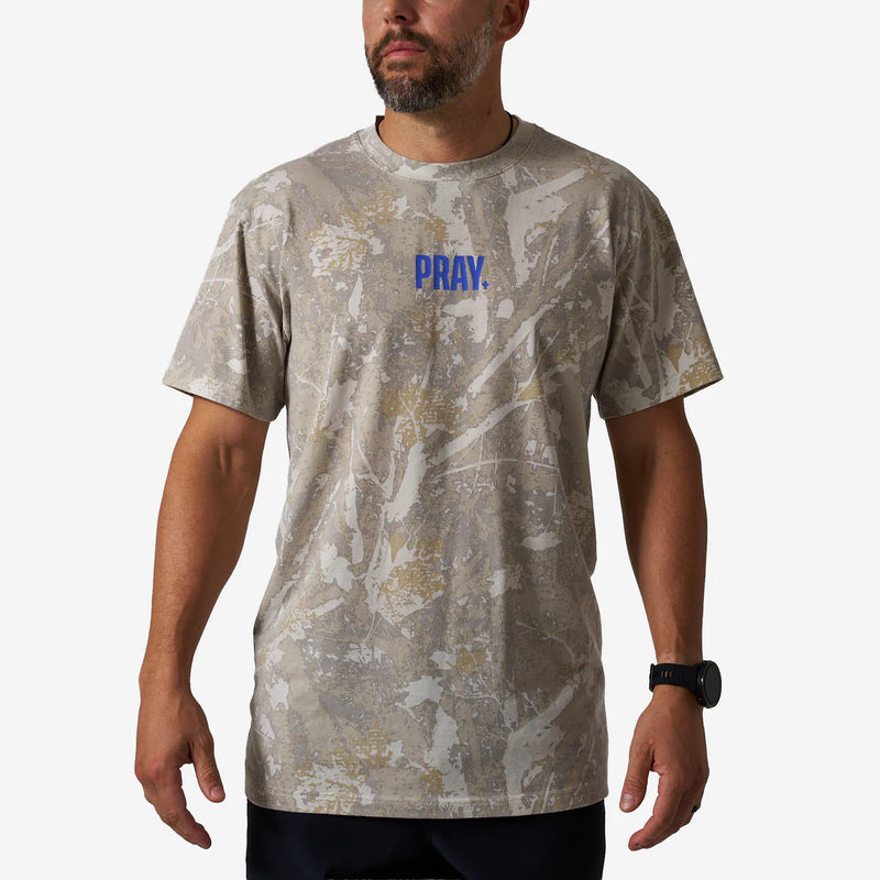 Man wearing a camouflage t-shirt with 'PRAY.' printed in blue on a white background