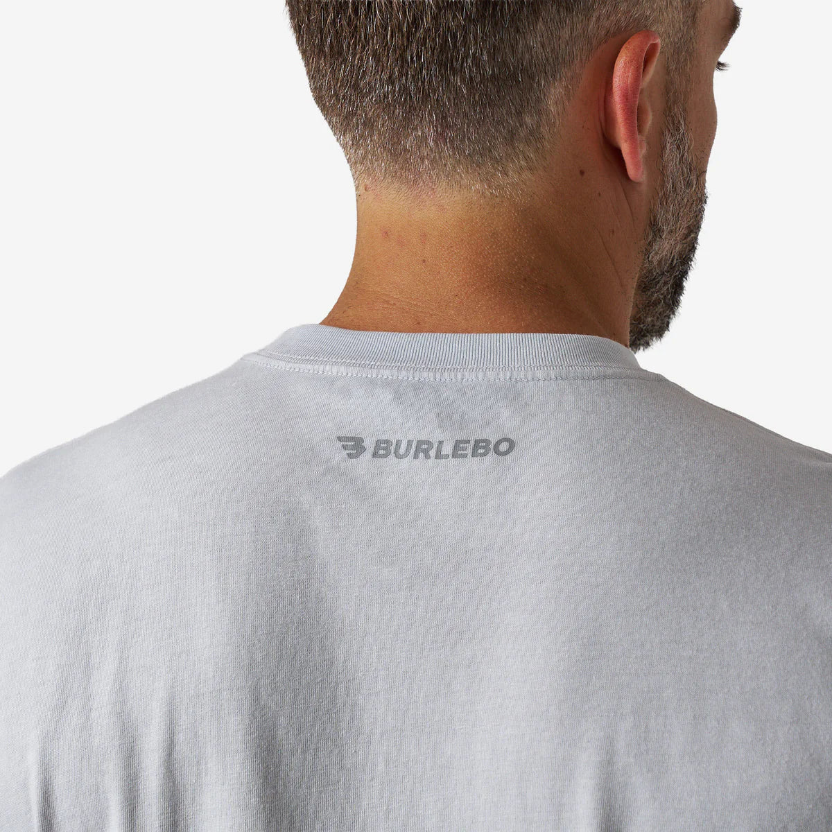 Gray t-shirt with 'Burlebo' logo on the back, worn by a person.