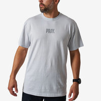 Man wearing a gray t-shirt with 'PRAY.' text on a white background
