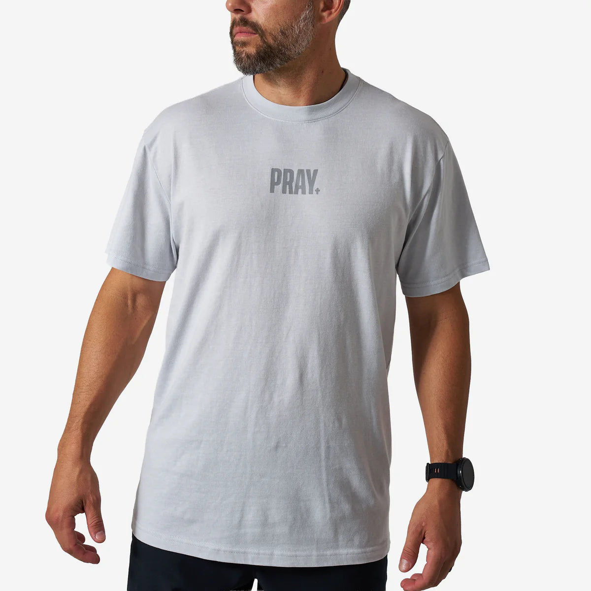 Man wearing a gray t-shirt with 'PRAY.' text on a white background