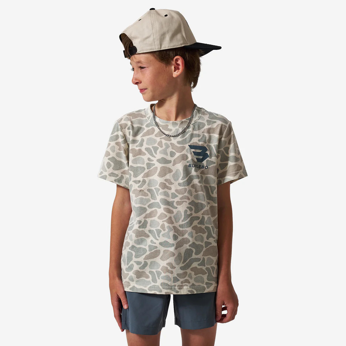 Child wearing a camouflage t-shirt with a logo and a cap on a white background