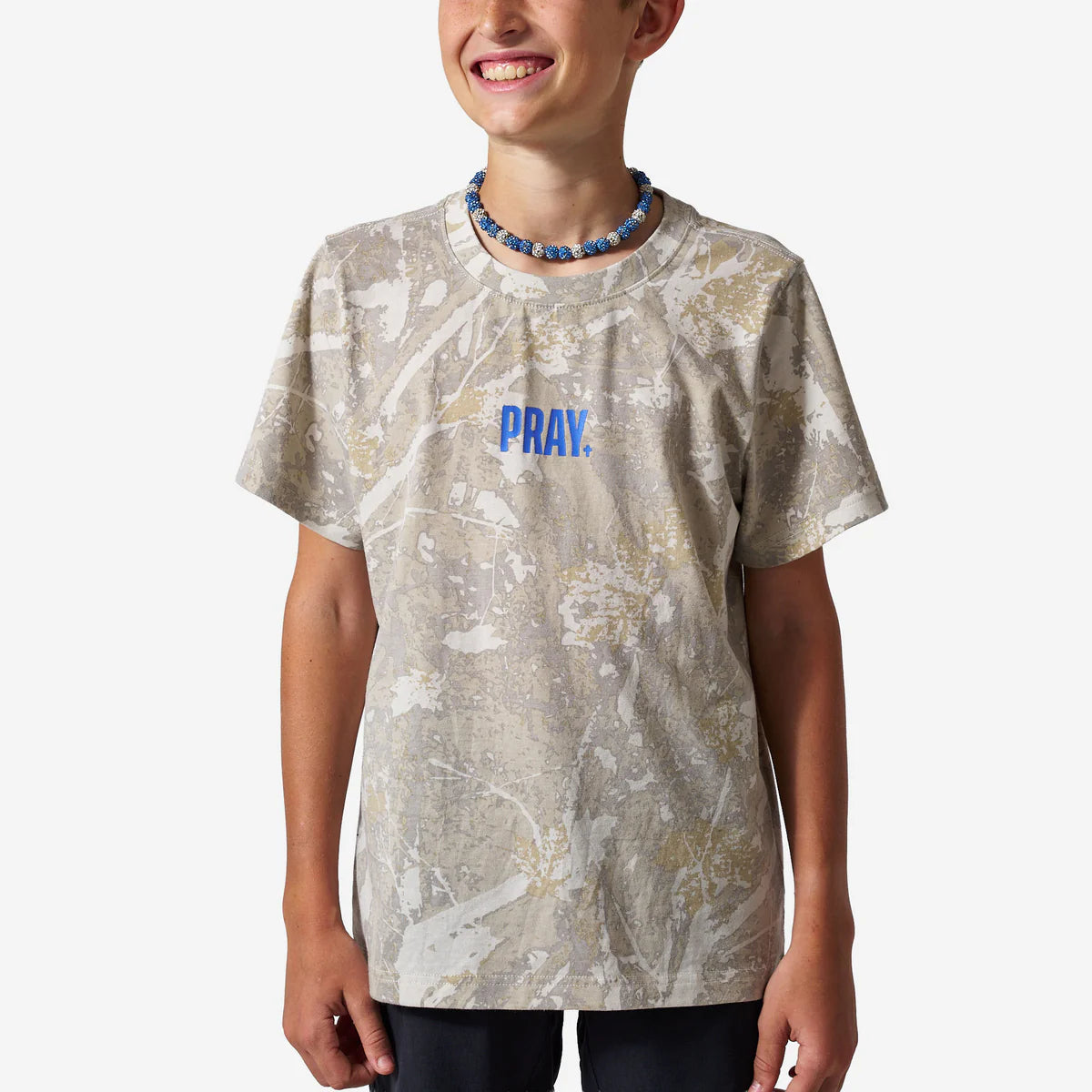 Person wearing a t-shirt with 'PRAY.' printed on it against a white background