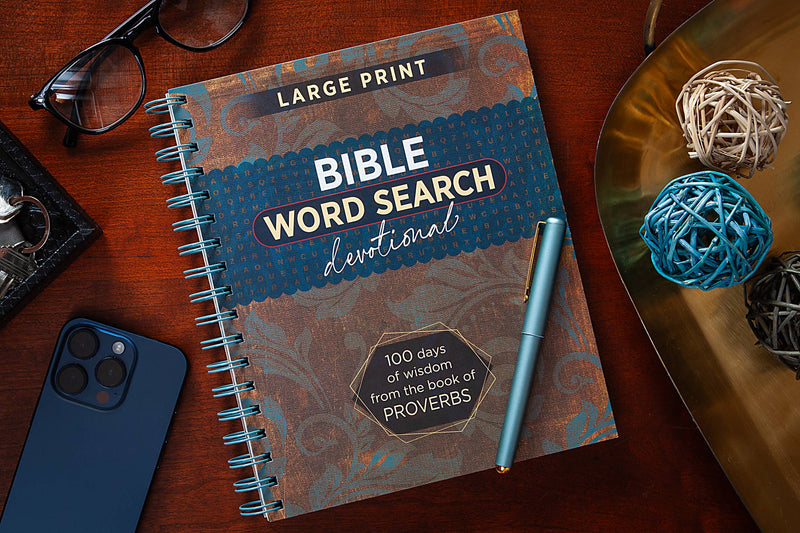 Bible Word Search devotional book on a wooden surface with a pen and phone.