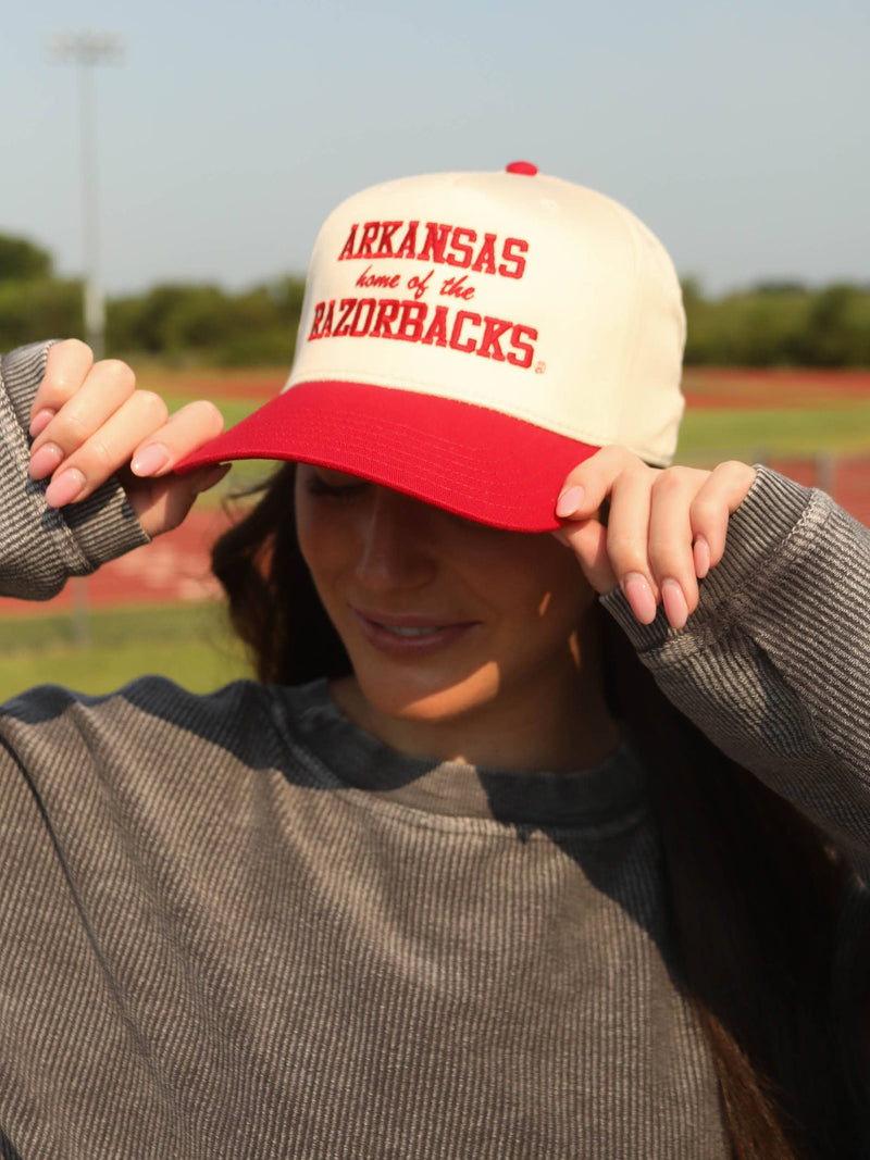 Person wearing a 'Arkansas Razorbacks' cap on a sports field