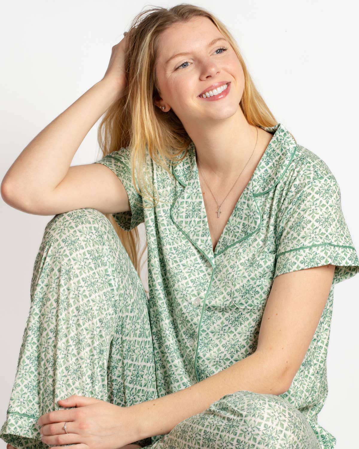 Woman wearing a green patterned outfit sitting on a white background
