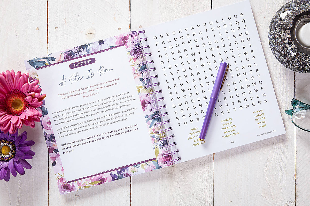 Open planner with floral design on a wooden surface with flowers and a pen.