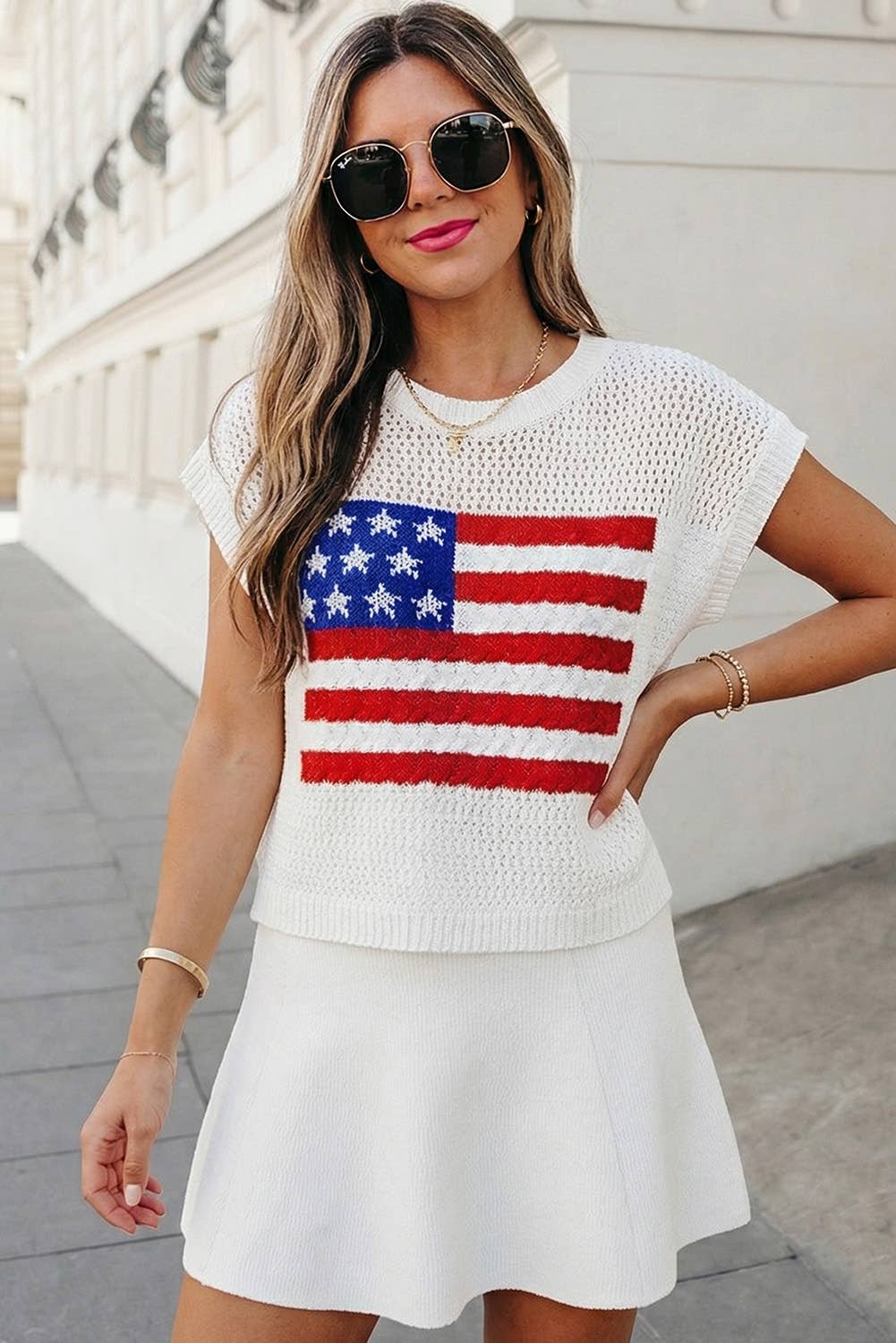 Woman wearing a white crochet top with an American flag design and a white skirt.