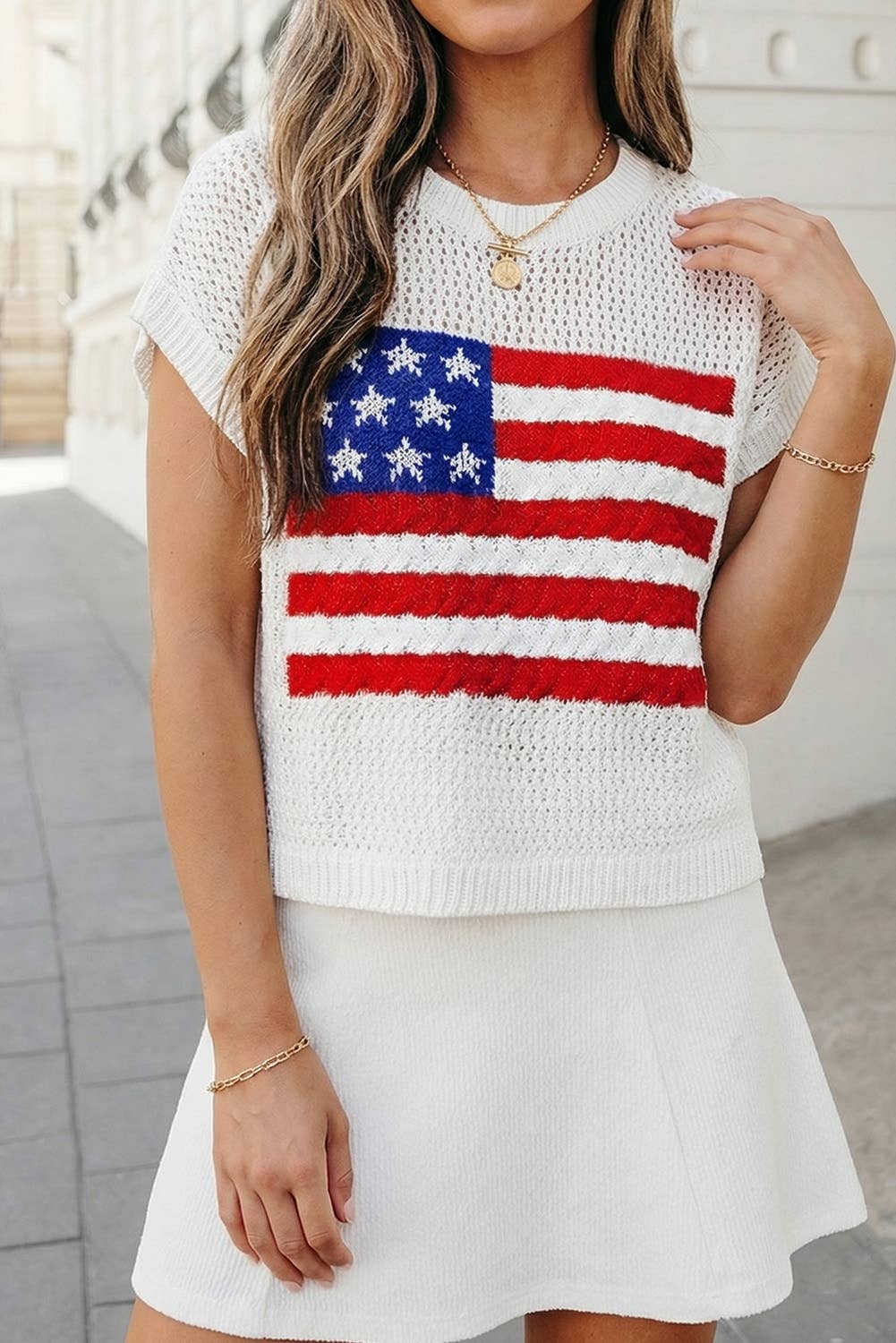 Woman wearing a white sleeveless top with an American flag design and a white skirt.