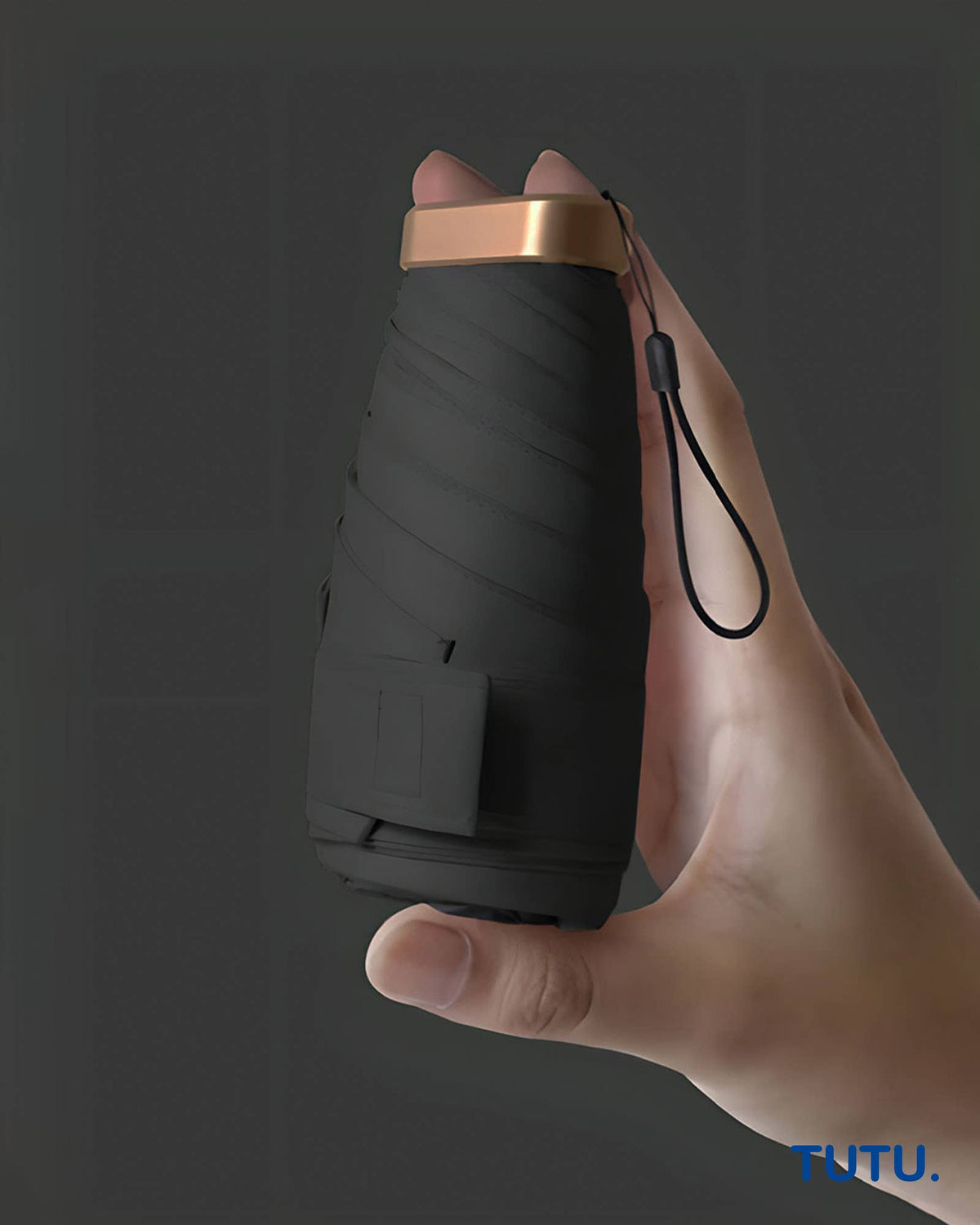 Hand holding a black folding knife with a brown handle against a dark background