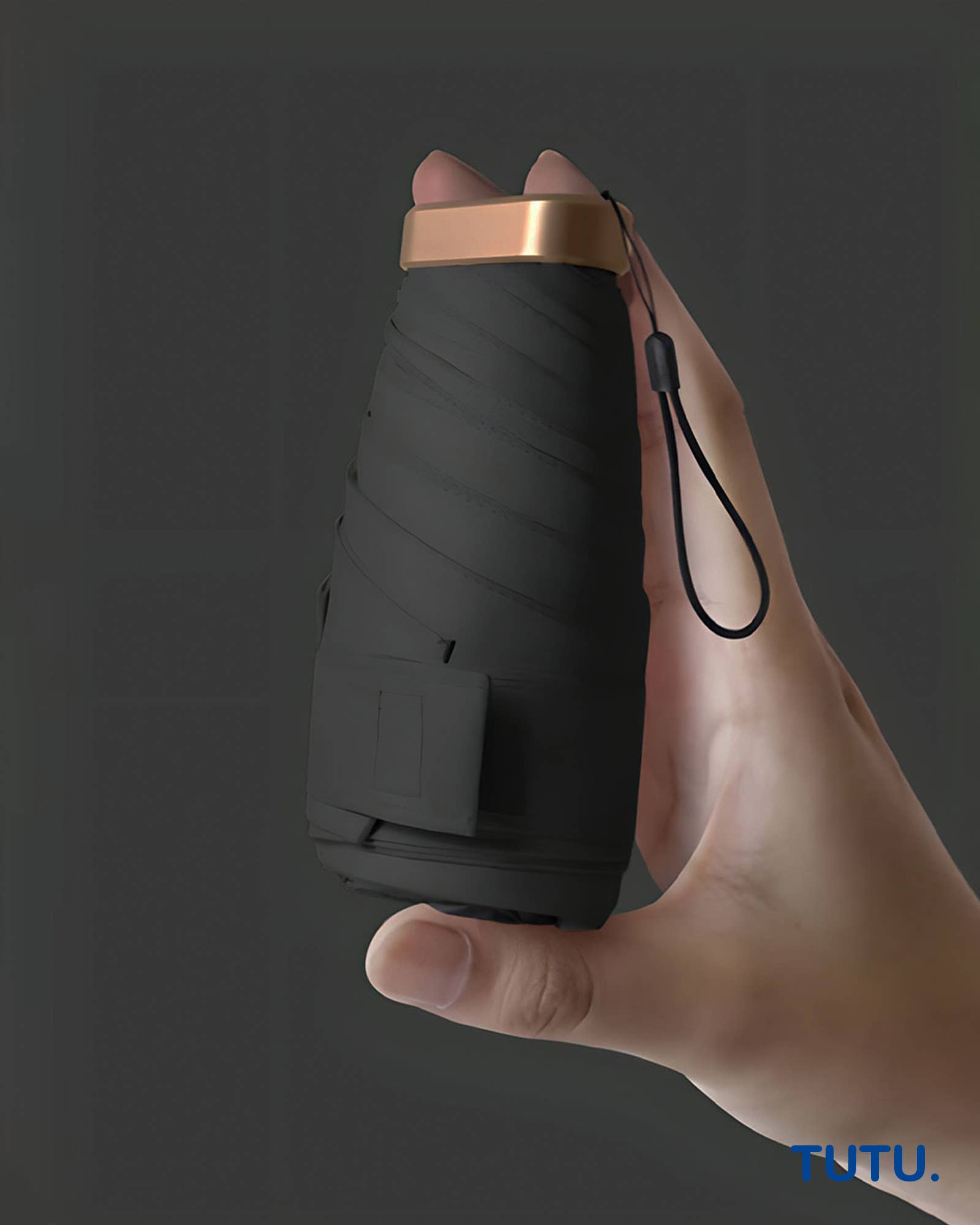 Hand holding a black folding knife with a brown handle against a dark background