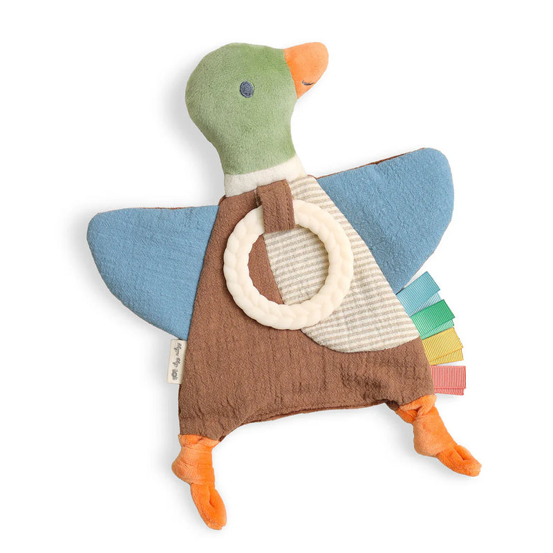 A duck-shaped baby teething toy with a green head, blue wings, brown body, orange beak and feet, a cream ring handle, and colorful fabric tabs along the tail, shown on a white background.