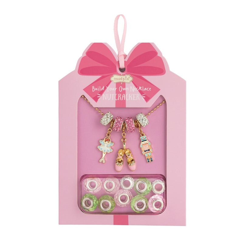 Pink jewelry set with charms and beads in a decorative box on a white background