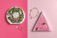 Christmas-themed jewelry and packaging on a pink background