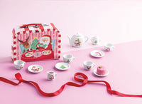 Children's Tea Set including tea pitcher, teacups, saucers, and sugar and creamer set with Santa and reindeer in a red and white striped box on a pink background.