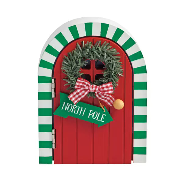 Red door with green wreath, bow, and 'North Pole' sign on a white background