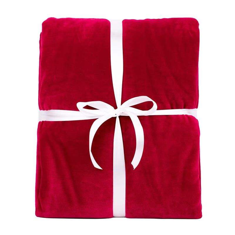 A folded plush red blanket tied with a white ribbon and bow, centered on a plain white background.