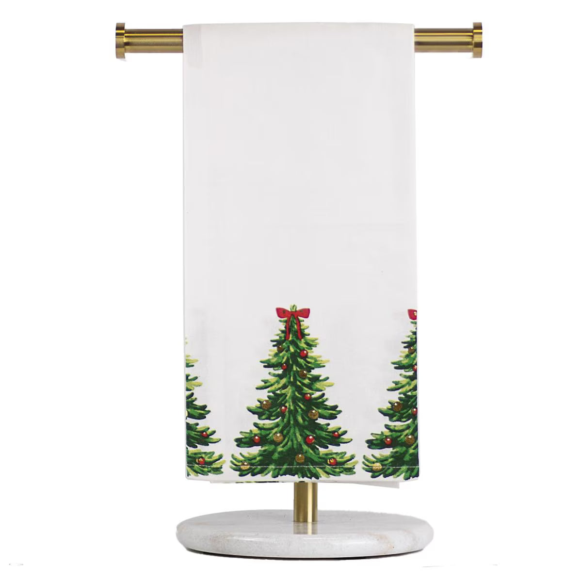 A white kitchen towel with a green Christmas tree pattern and red bows, hanging from a gold metal rod on a round white marble stand against a white background.