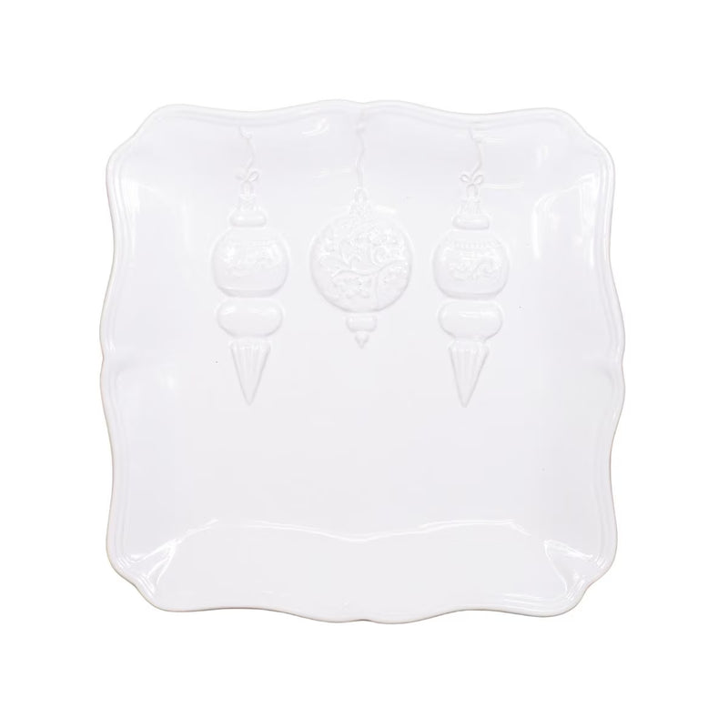 A white ceramic serving platter with a scalloped edge and embossed hanging ornament designs, shown on a plain white background.