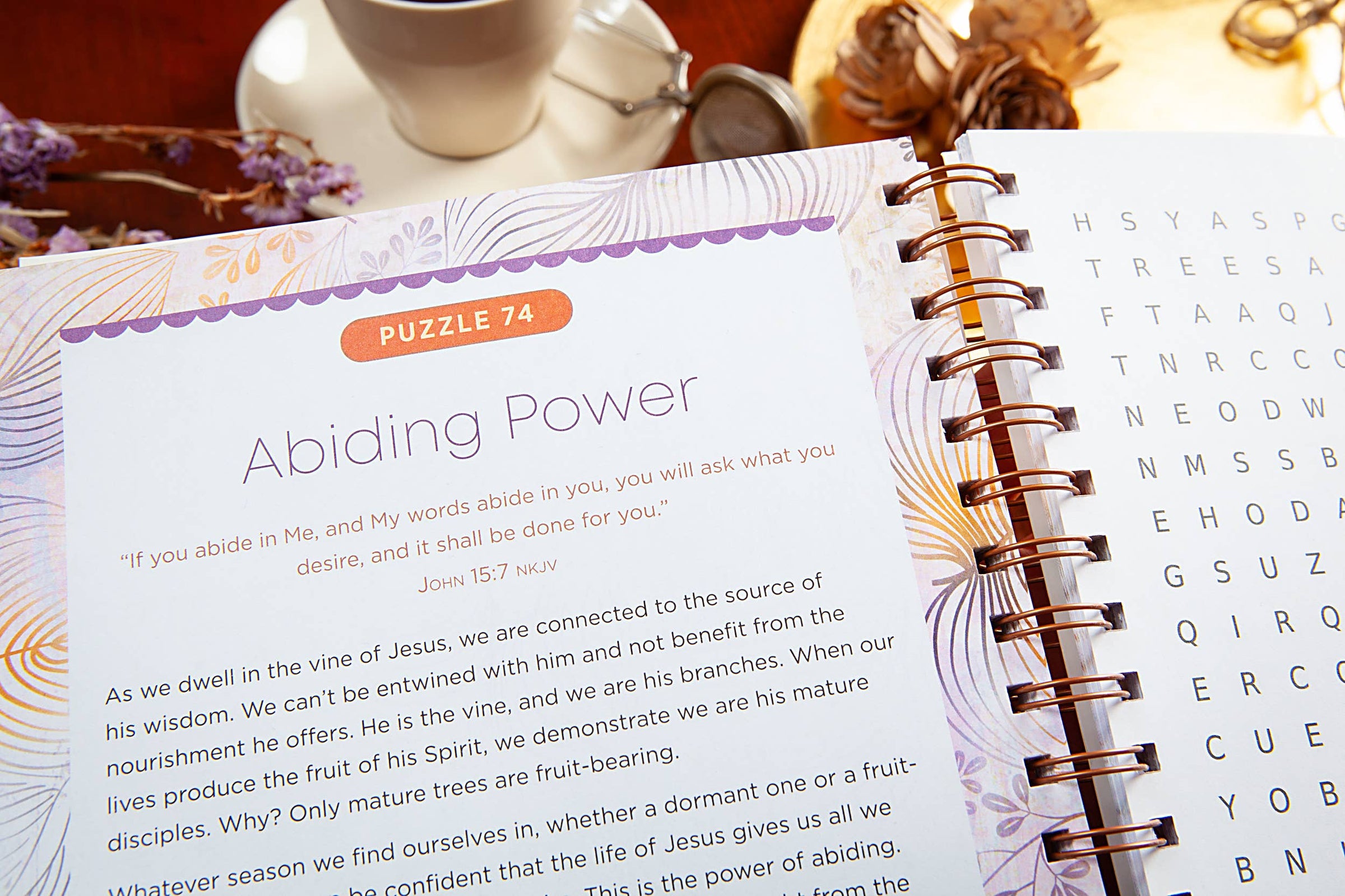 Open book with a puzzle titled 'Abiding Power' on a table with a cup and decorative items.