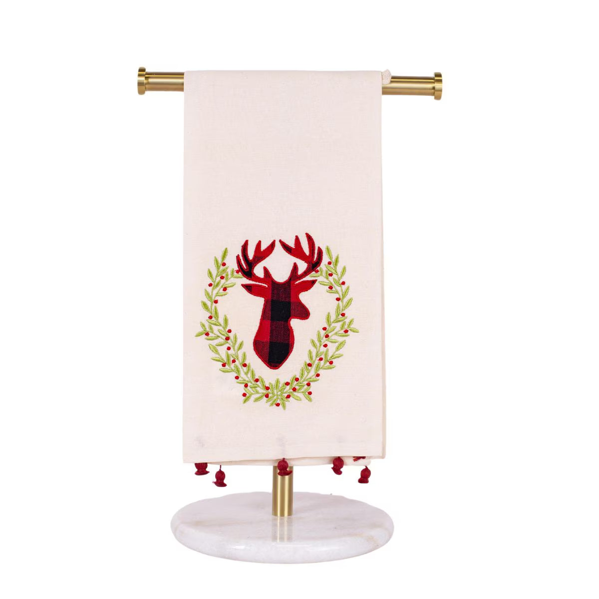 An off-white kitchen towel with a red and black buffalo plaid deer head wreath design, hanging from a gold metal stand with a marble base.