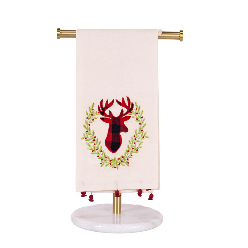 An off-white kitchen towel with a red and black buffalo plaid deer head wreath design, hanging from a gold metal stand with a marble base.