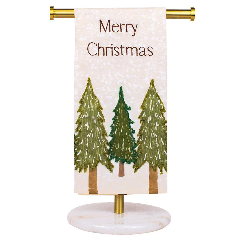 A vertical Christmas banner flag with a white glittery background, featuring the text 'Merry Christmas' in brown and three green pine tree illustrations. The banner is displayed on a gold metal stand with a round white marble base, set against a plain white background.