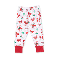 White Christmas-themed pajama pants with an all-over print of red bows, candy canes, holly, and green peppermint candies, finished with solid red ankle cuffs.