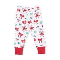 White children's pajama pants with a festive Christmas print featuring red bows, candy canes, holly, and green candy canes, finished with solid red ankle cuffs.