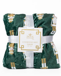 Green throw blanket with nutcracker pattern and 'Royal Standard' label on a white background