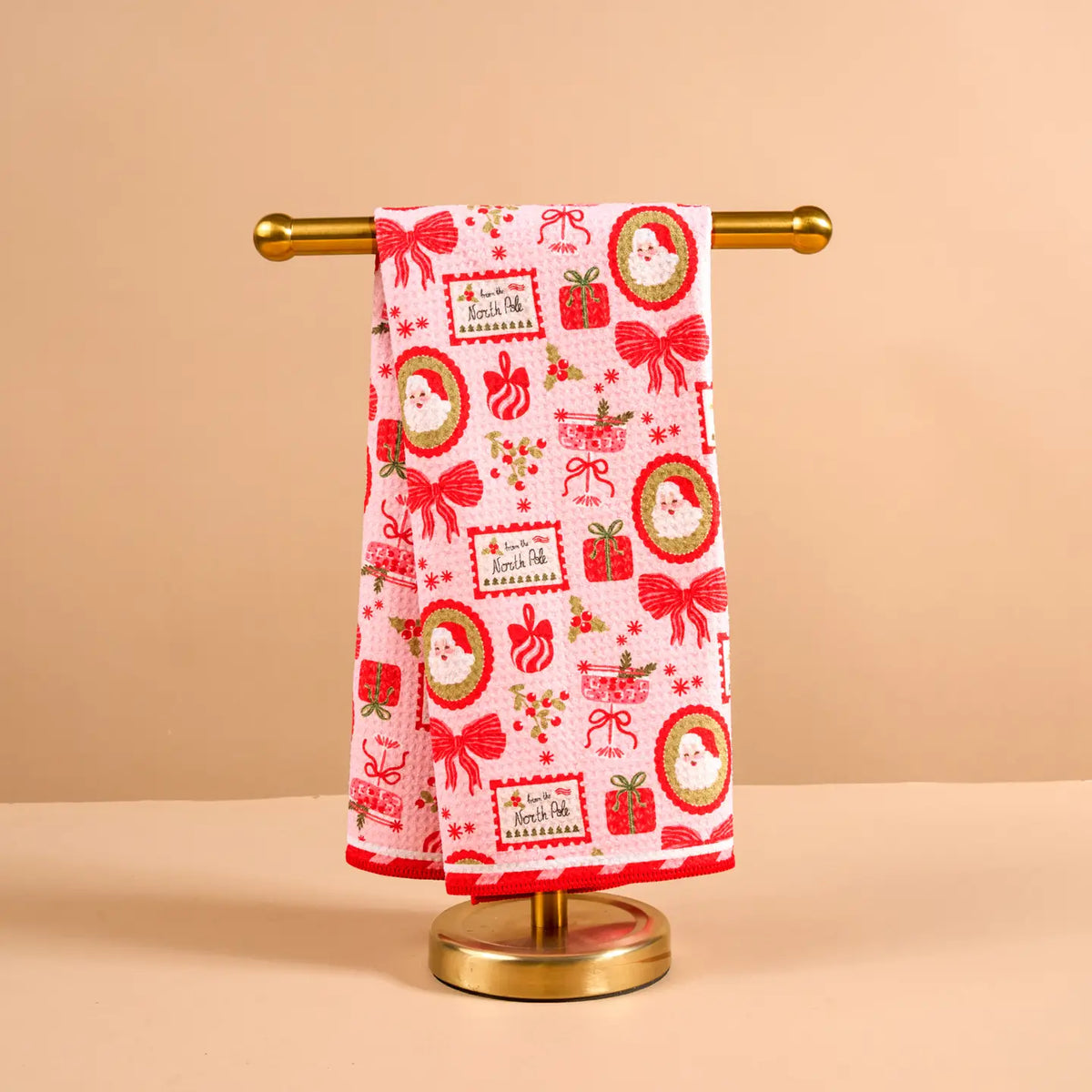 Decorative towel with Christmas patterns on a gold stand against a beige background