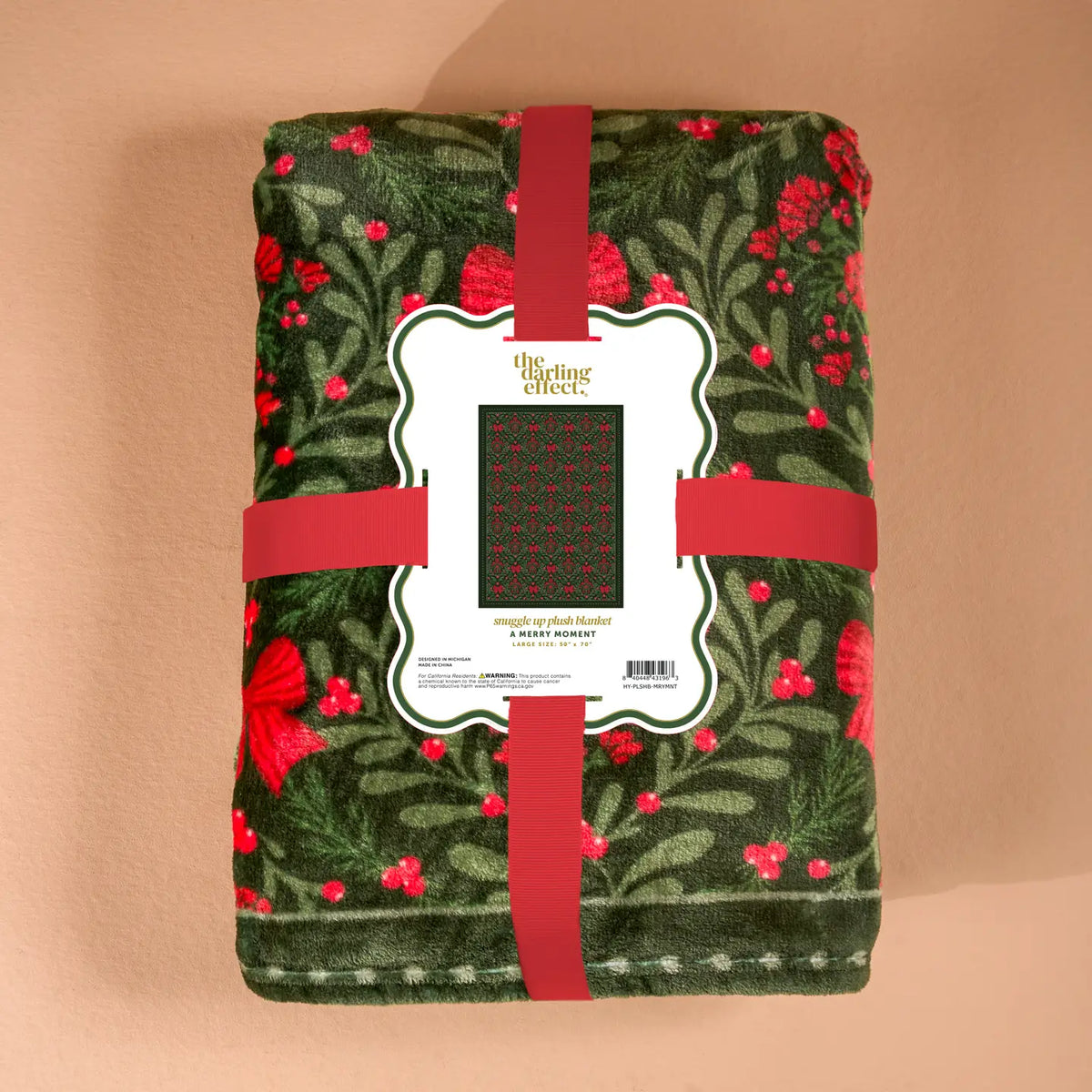 Green blanket with red floral pattern and red ribbon on a beige background