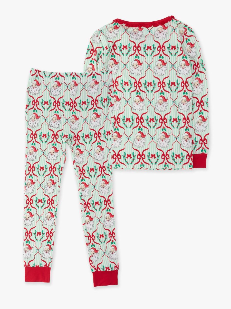 A two-piece children's pajama set featuring a long-sleeve top and matching pants with a festive Christmas-themed pattern of Santa Claus, reindeer, and red bows on a white background with red ribbed trim.