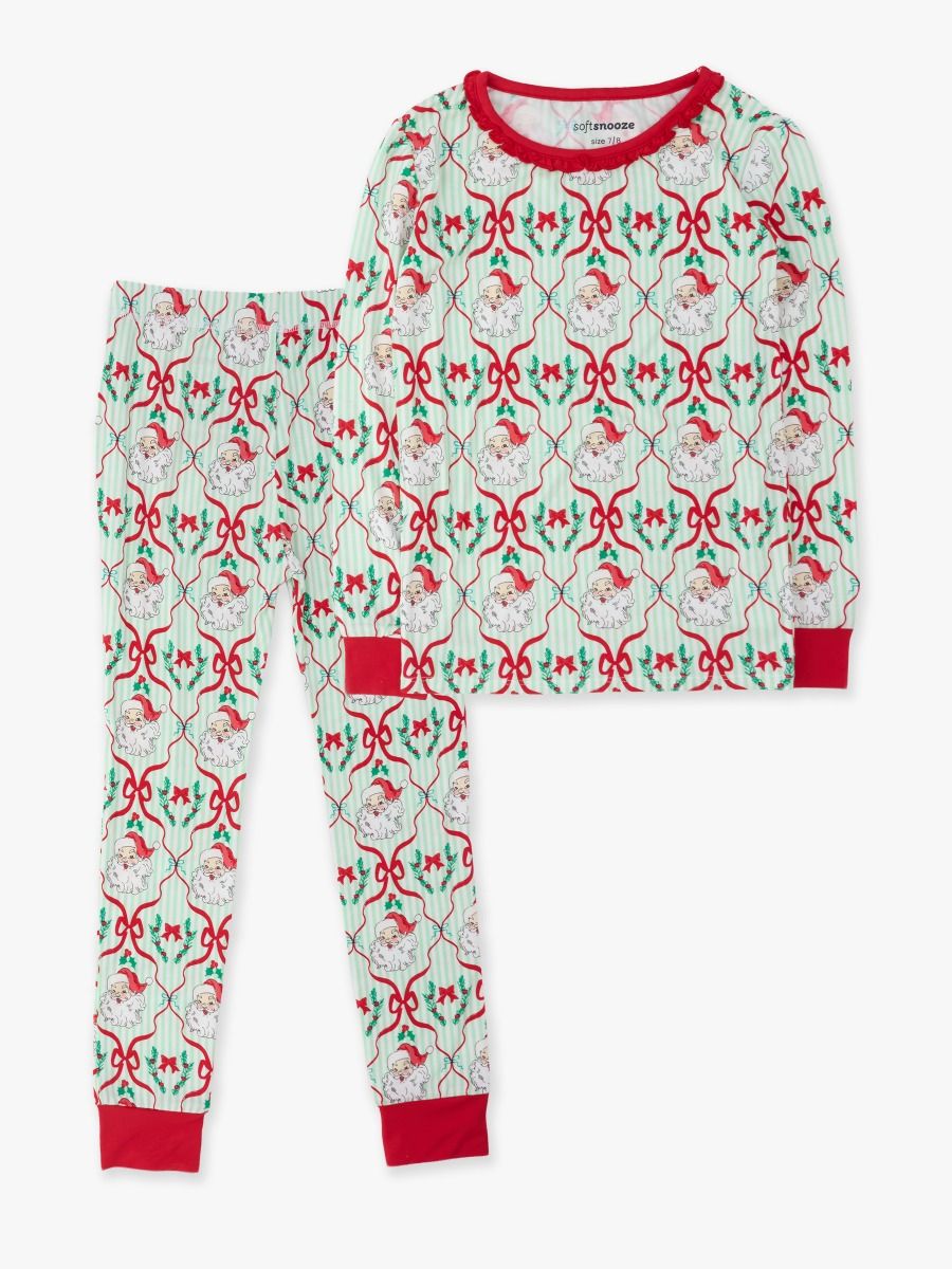 A two-piece children's pajama set featuring a long-sleeve top and matching pants with a festive Christmas pattern of red bows, green mistletoe, and Santa Claus silhouettes on a white background, with red trim.