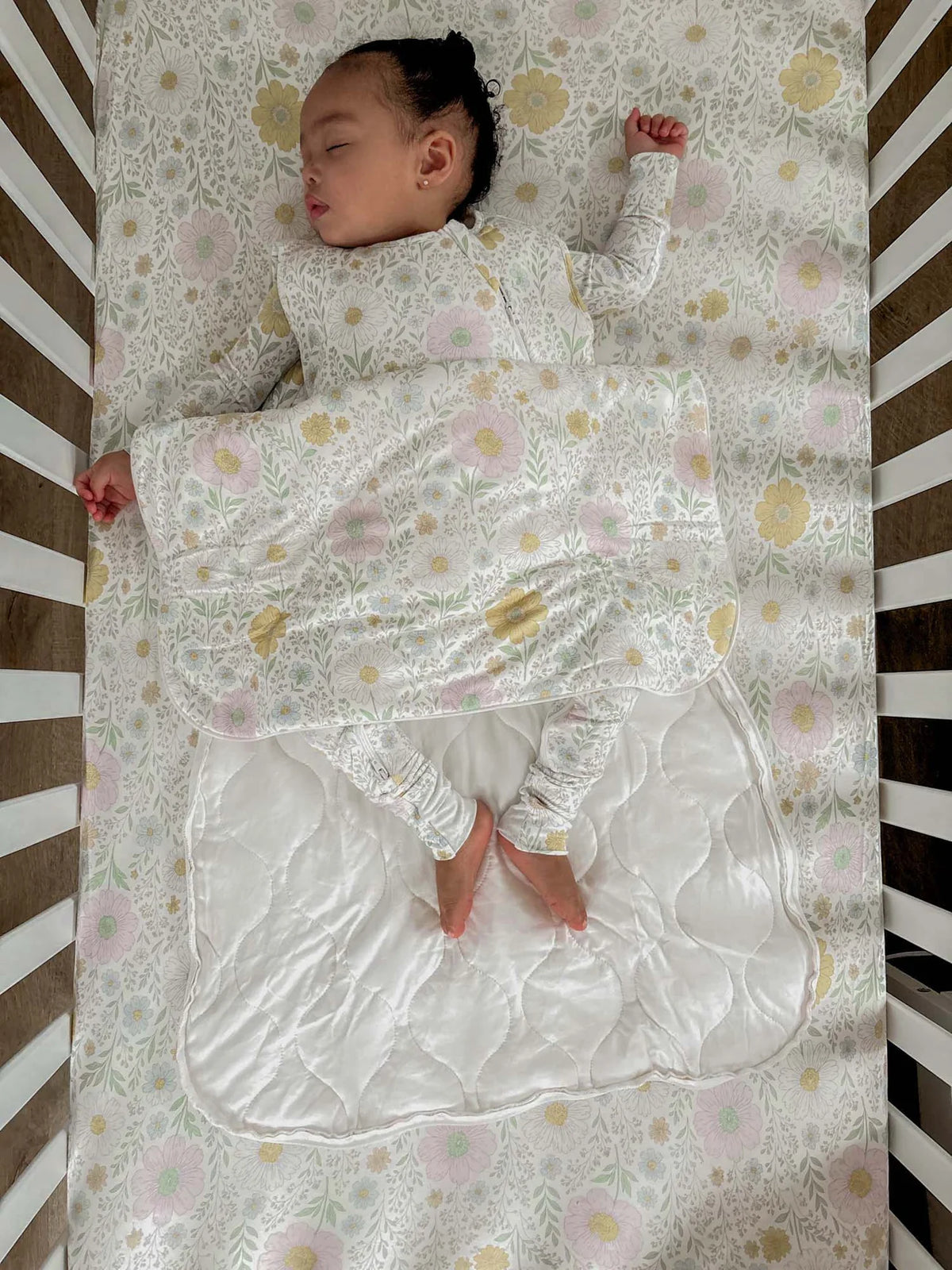 Baby sleeping in a crib with a floral-patterned sheet