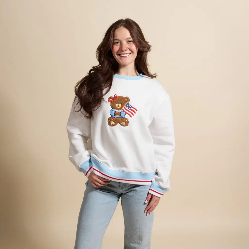 Woman wearing a white sweatshirt with a teddy bear design on a beige background