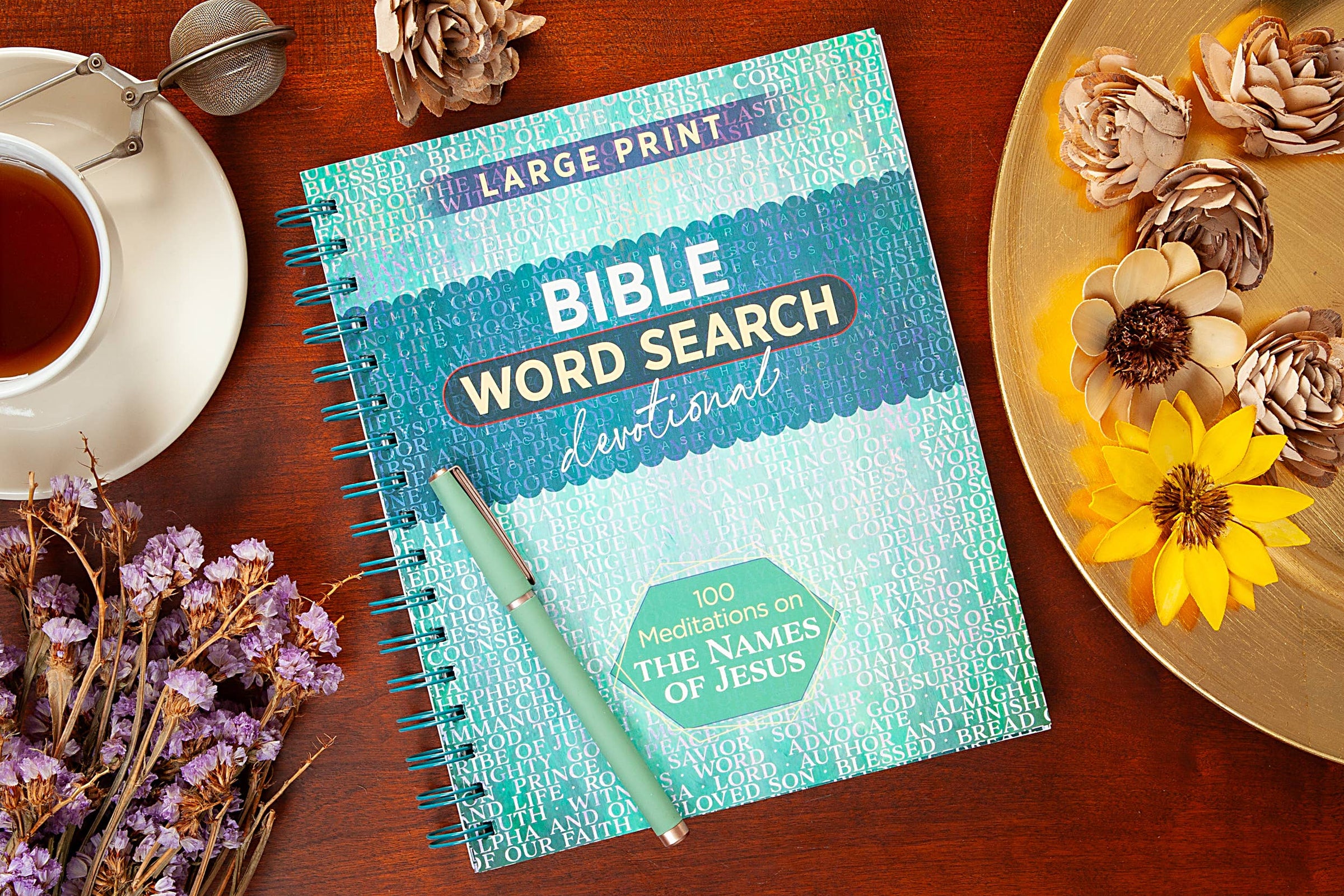 Bible Word Search Devotional book on a wooden table with flowers and a cup of tea.