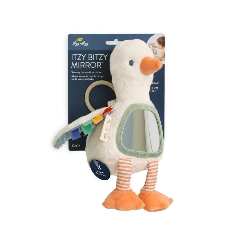 A plush duck toy with a built-in mirror, orange beak and feet, striped legs, and rainbow feather accents, shown hanging in front of its dark blue retail card packaging on a white background.