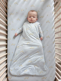 Baby wrapped in a light blue swaddle with star pattern lying on a crib.