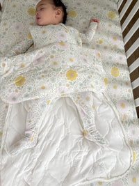 Baby lying on a floral-patterned blanket with a white bib.
