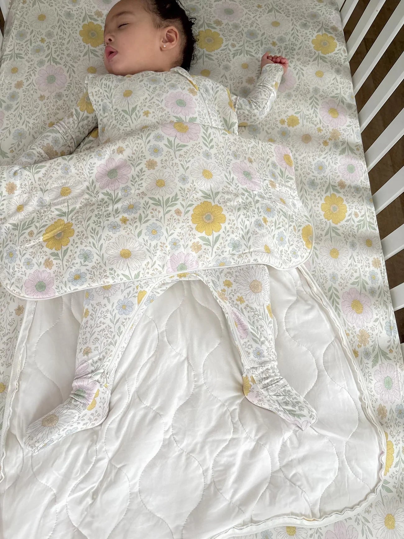 Baby lying on a floral-patterned blanket with a white bib.