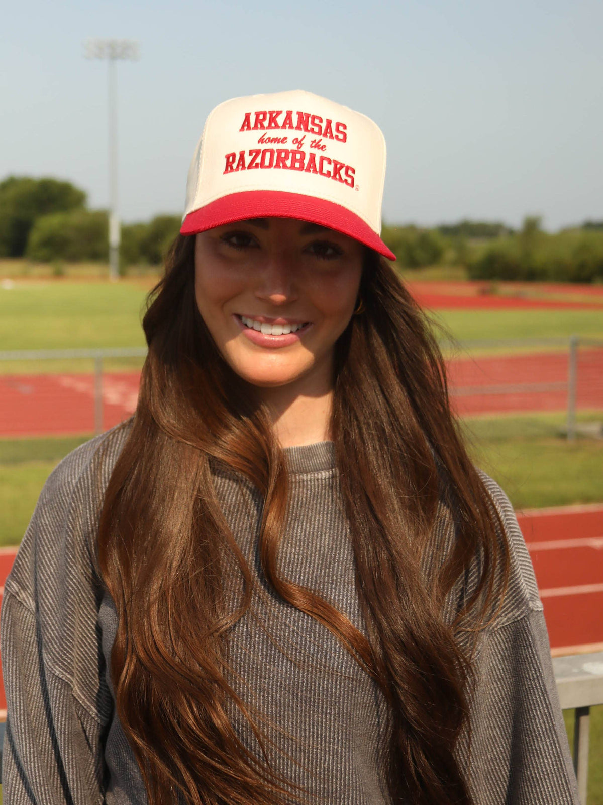 Person wearing an Arkansas Razorbacks cap on a sports field