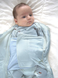Baby wrapped in a light blue swaddle on a white blanket